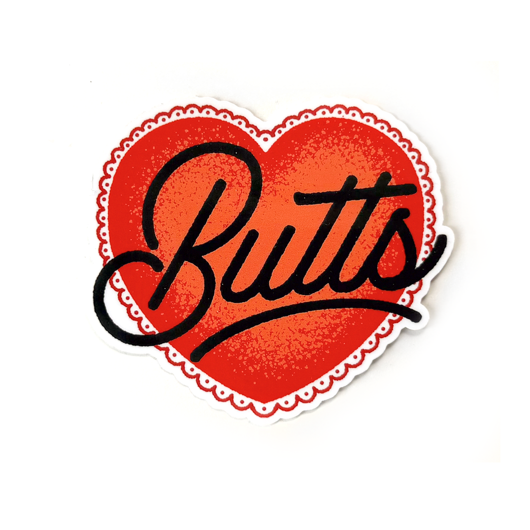 A red heart-shaped sticker with a white scalloped border and the word Butts written in black cursive text across the center.