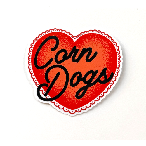 Red heart sticker with black hand-drawn script typography reading “Corn Dogs” in a clean, minimalist food-inspired style.