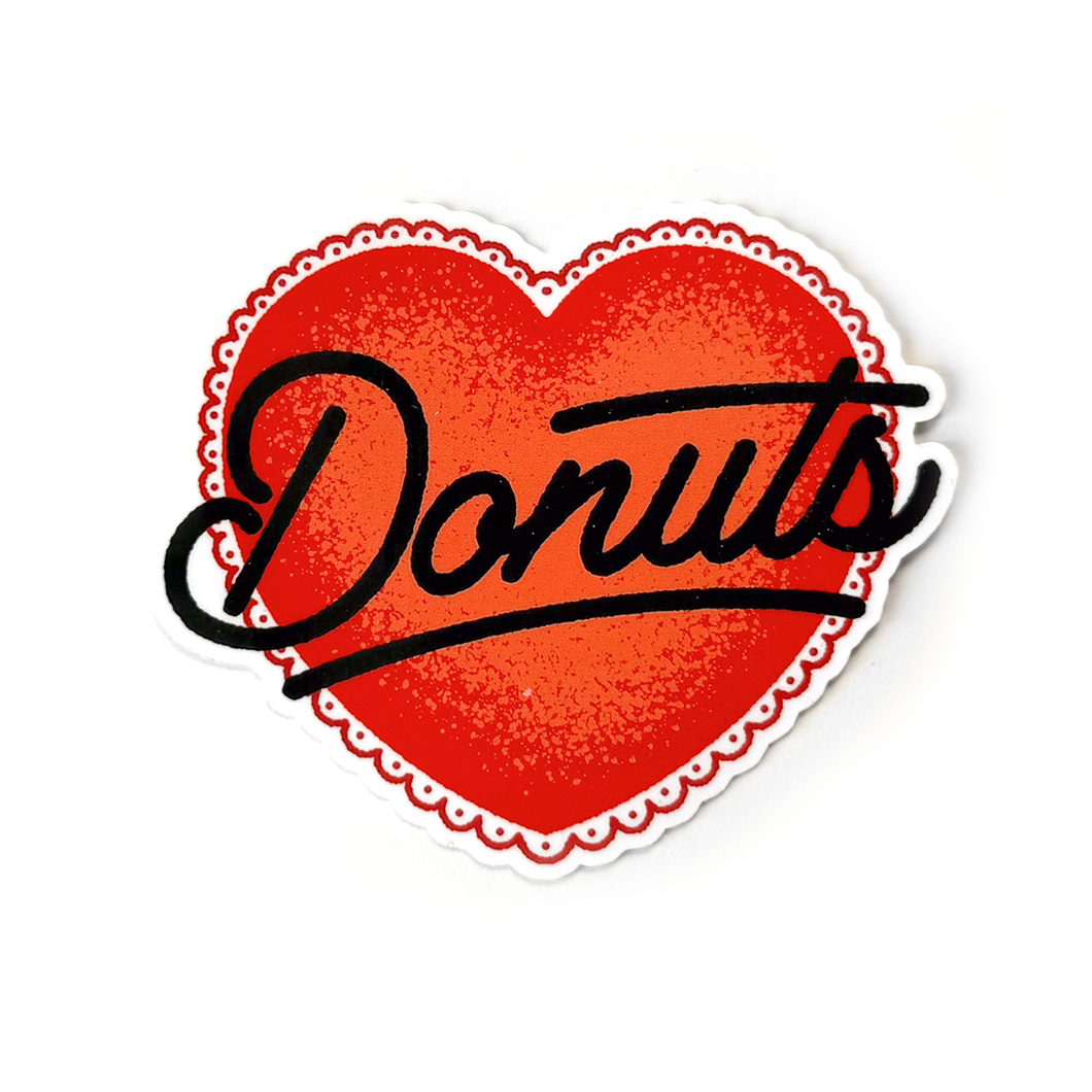 A red heart-shaped sticker with a white scalloped border and the word Donuts written in black cursive text across the center.