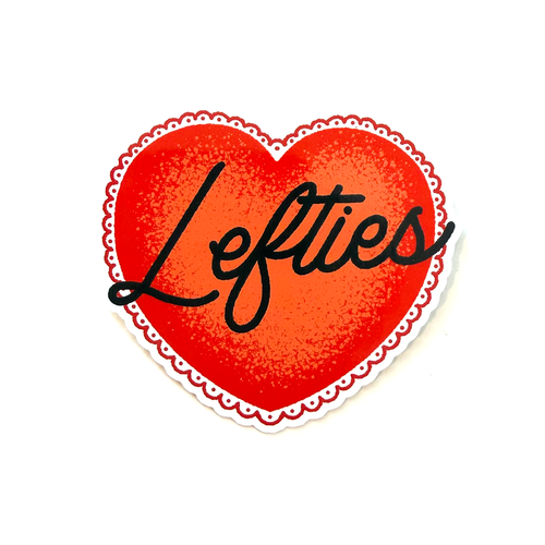 Red heart sticker with black hand-drawn script typography reading “Lefties” in a clean, minimalist politically inspired style.