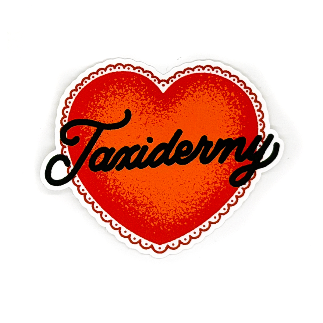 A red heart sticker with a scalloped border and stippled shading featuring the word Taxidermy written across the center in black cursive text.